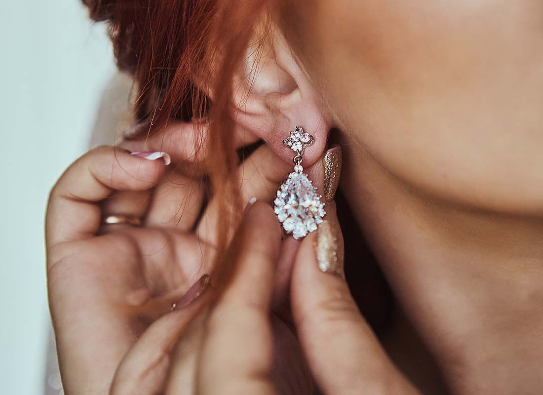 Valuable Possessions Insurance - Close-up of the Manicured Hands of a Young Woman Placing Her Expensive Earrings into Ears for a Special Occasion